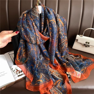 Detail of silk-like scarf with paisley pattern draped against a premium leather backdrop