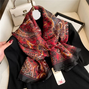 Close-up of red paisley silk scarf with vintage patterns on a black knit top