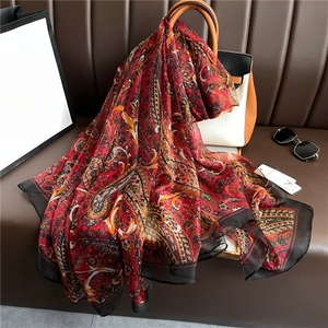 Elegant red paisley silk-like scarf draped on a bag, stylish sun protection long shawl