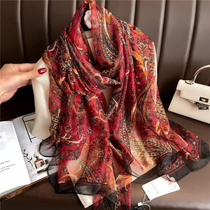 Detail of red paisley silk scarf with black border showing elegant drape and light texture