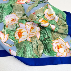 Detailed shot of silk scarf featuring lotus floral print and royal blue border detail