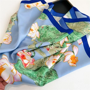Close-up of silk scarf showing lotus print and deep blue border contrast texture