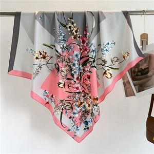 Detail of soft pink floral silk scarf hanging on a metal bar with minimal background