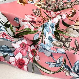Close-up of pink silk scarf featuring elegant floral patterns and twill texture details