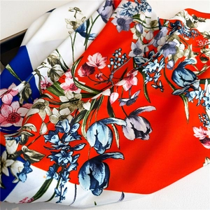 Macro view of silky floral scarf featuring bright red tulips and white-blue stripes