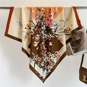 Close-up of floral print silk scarf with orange and brown geometric patterns and flowers