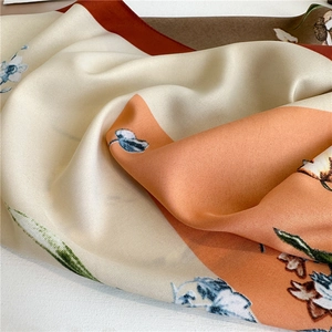Detail of printed silk scarf showing soft folds with orange geometric pattern and blue floral print