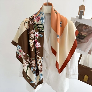 Elegant floral silk square scarf with orange and brown patchwork hanging on a white blazer