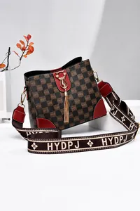 Detailaufnahme der dunkelbraunen Tasche mit Karomuster, rotem Rand und goldener Hardware