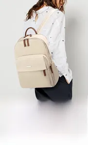 Détail du sac à dos crème avec accents en cuir marron et poche zippée frontale
