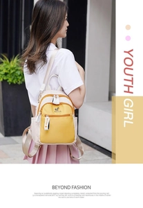 Detail view of the contrasting yellow and beige backpack on model in urban setting