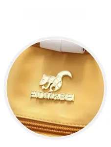 Detail of golden squirrel logo and metallic brand emblem on a yellow travel backpack