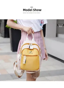 Detail of small color-block backpack with yellow accent and decorative logo strap