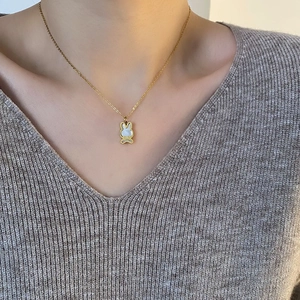 Collier lapin doré élégant avec incrustation de nacre porté par un mannequin sur un pull