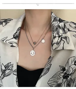 Detail of layered silver necklaces with hollow smiley face and solid bead charms on model