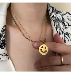 Detail of layered gold smiley face pendant necklace and matching ring on model