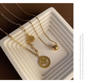Detailed view of gold smiley face pendants on box and paperclip link chains