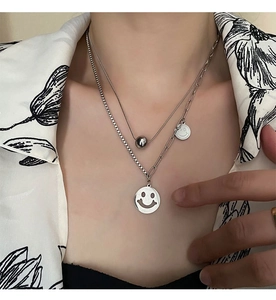 Detailed view of layered titanium steel necklace with hollow smiley face pendant on model