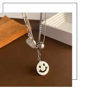 Detail of silver double-layered necklace featuring hollow smiley face pendants on dark leather