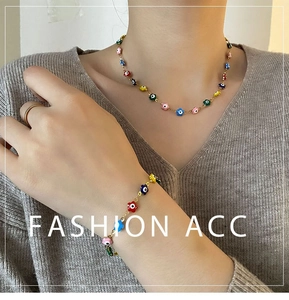 Détail de l'ensemble collier et bracelet à fleurs émaillées et œil porte-bonheur