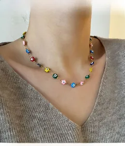 Gros plan d'un collier doré avec pendentifs fleurs colorés et motifs œil sur un mannequin