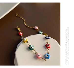 Vue détaillée des breloques fleurs mauvais œil sur un bracelet plaqué or