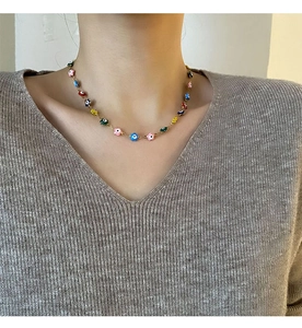 Détail d'un collier de fleurs œil maléfique colorées sur chaîne dorée porté par un mannequin
