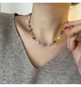 Gros plan du collier fleur émaillé multicolore avec œil protecteur sur chaîne dorée