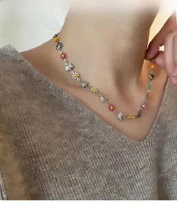 Detail of necklace with colorful enamel daisies and silver butterfly charms on model
