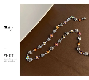 Detail of colorful enamel daisy charms and silver butterfly links on a steel necklace