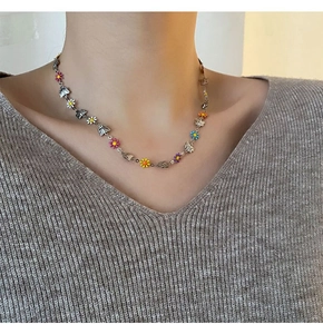 Close-up of a necklace featuring multi-colored enamel daisies and silver metal butterflies