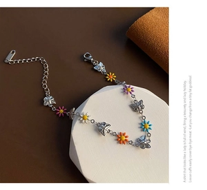 Detail of silver daisy bracelet with colorful enamel petals and butterfly charms