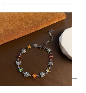 Detailed shot of silver butterfly chain with colorful enamel daisy pendants and lobster clasp
