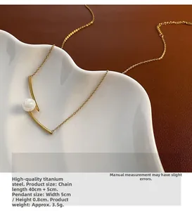 Detail of titanium steel gold pearl necklace showing curved design on ceramic plate