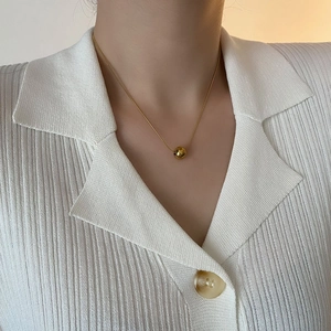 Élégant collier à chaîne serpent dorée avec un pendentif perle ronde sur un mannequin