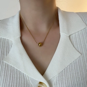 Collier chaîne serpent dorée minimaliste avec perle polie porté par un mannequin femme