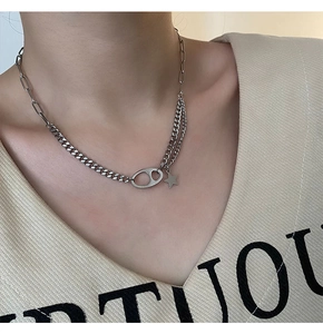 Close-up of a silver-toned pig nose link necklace with star pendant on a model