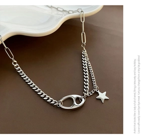 Close-up of silver pig-nose chain necklace with star pendant on leather background