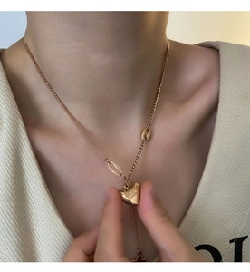 Close-up of golden double-layer necklace with heart pendant and Love engraving