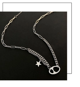 Detail of silver asymmetric paperclip and Cuban link necklace with star pendant