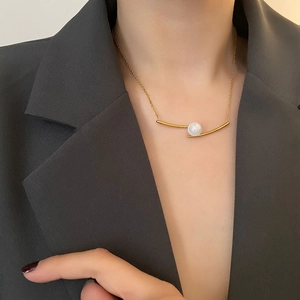 Minimalist gold titanium steel choker featuring a curved bar and glossy pearl pendant