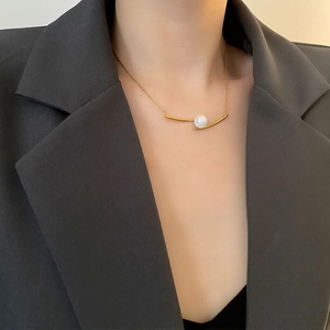 Minimalist titanium steel necklace with curved gold pendant and white pearl on a model