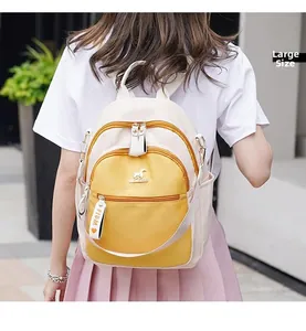 Detail view of large beige and yellow backpack with a kangaroo logo and ribbon charm