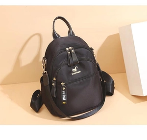 Detail of black nylon backpack featuring gold kangaroo logo and decorative logo ribbon