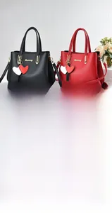 Detail of red and black leather handbags featuring litchi texture and gold hardware accents