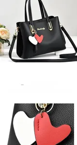 Close-up of black lychee leather texture and heart-shaped pendant on stylish handbag