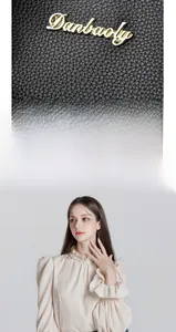 Macro detail of black litchi grain leather texture and gold brand logo on a handbag