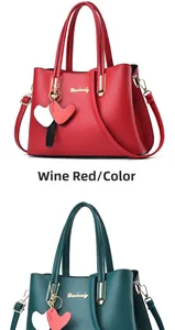 Detail of red and dark green leather handbags with heart charms and metal logo