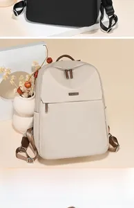 Detail of minimalist beige nylon backpack with brown leather handle and metal logo