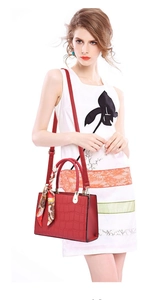 Red crocodile embossed handbag with silk scarf detail worn by a model in floral dress